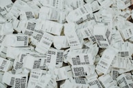A large number of white cartons with black text saying 'Boxed Water is Better' are piled together. The cartons have graphics and text promoting sustainability.