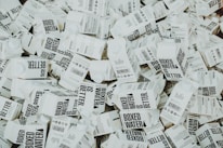 A large number of white cartons with black text saying 'Boxed Water is Better' are piled together. The cartons have graphics and text promoting sustainability.