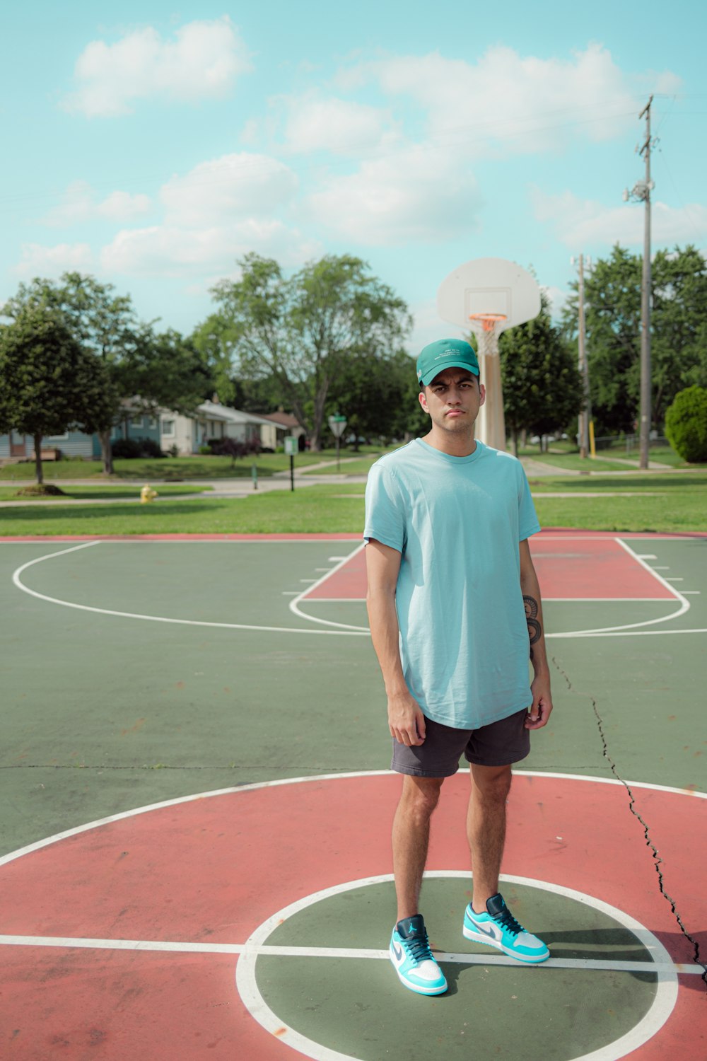 man in white crew neck t-shirt and black shorts standing on track field during daytime