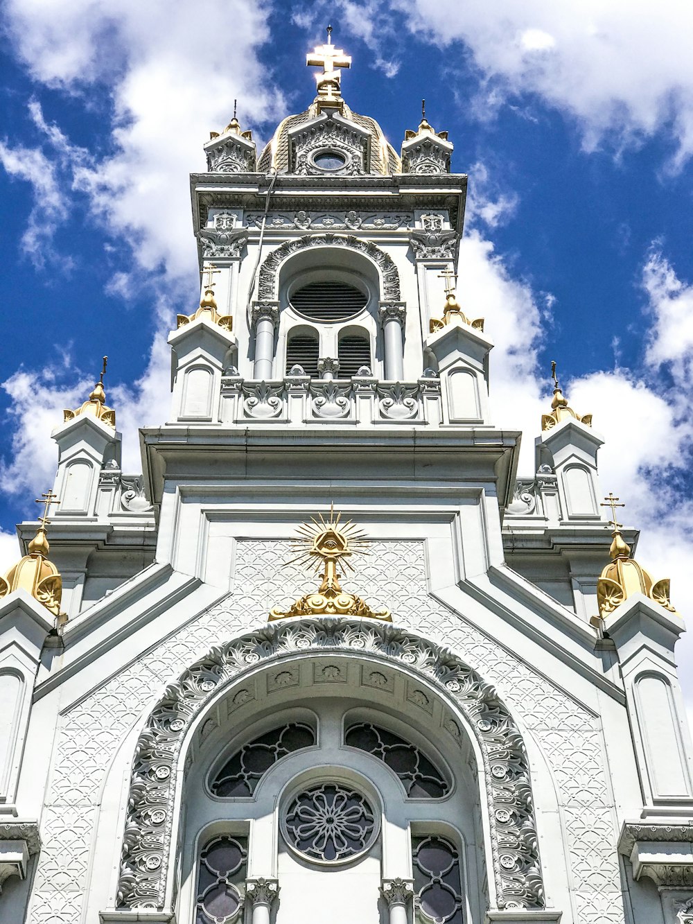 white and brown concrete church under blue sky and white clouds during daytime