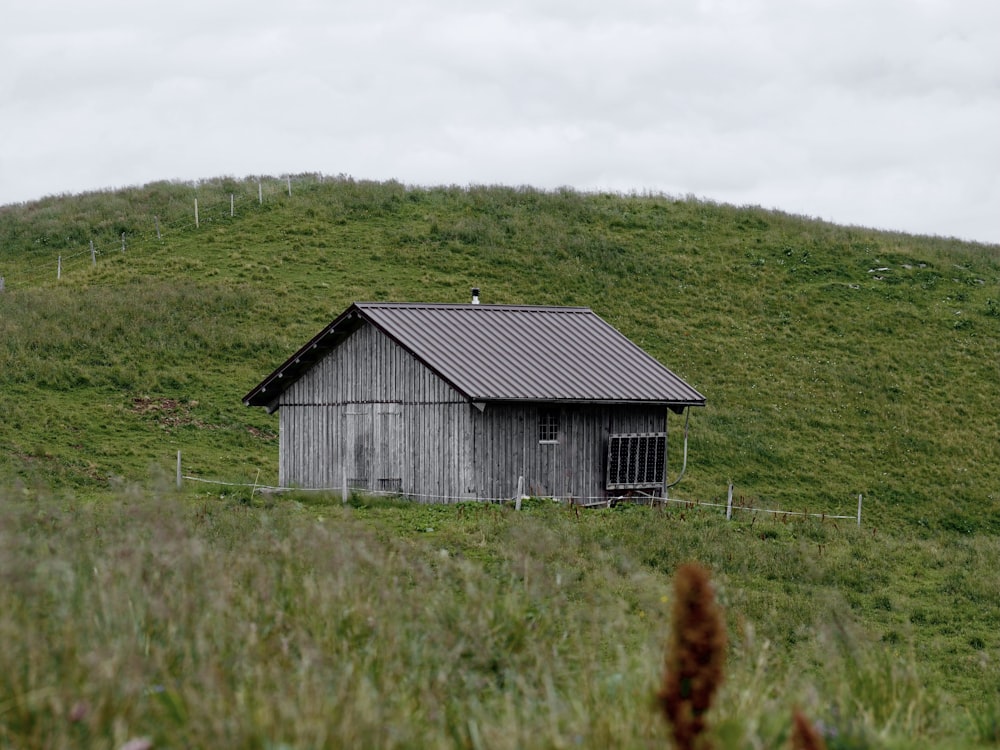 gray wooden house on green grass field during daytime