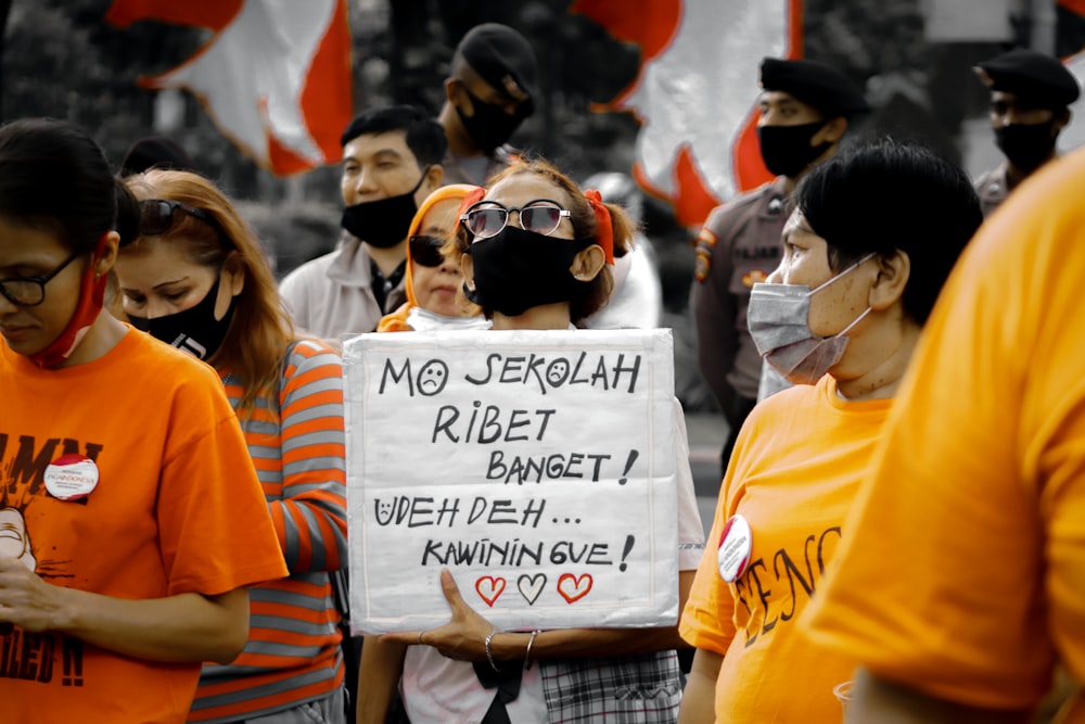 woman in orange t-shirt holding white printer paper