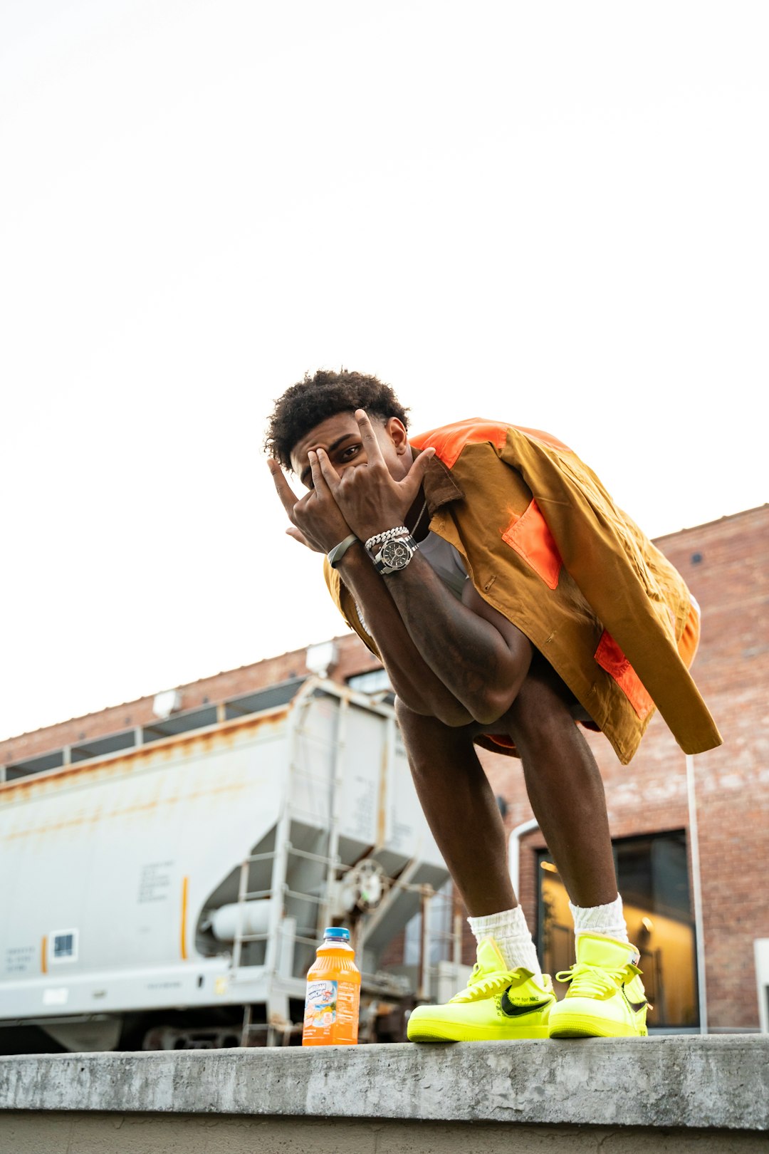 man in orange jacket and brown pants standing during daytime