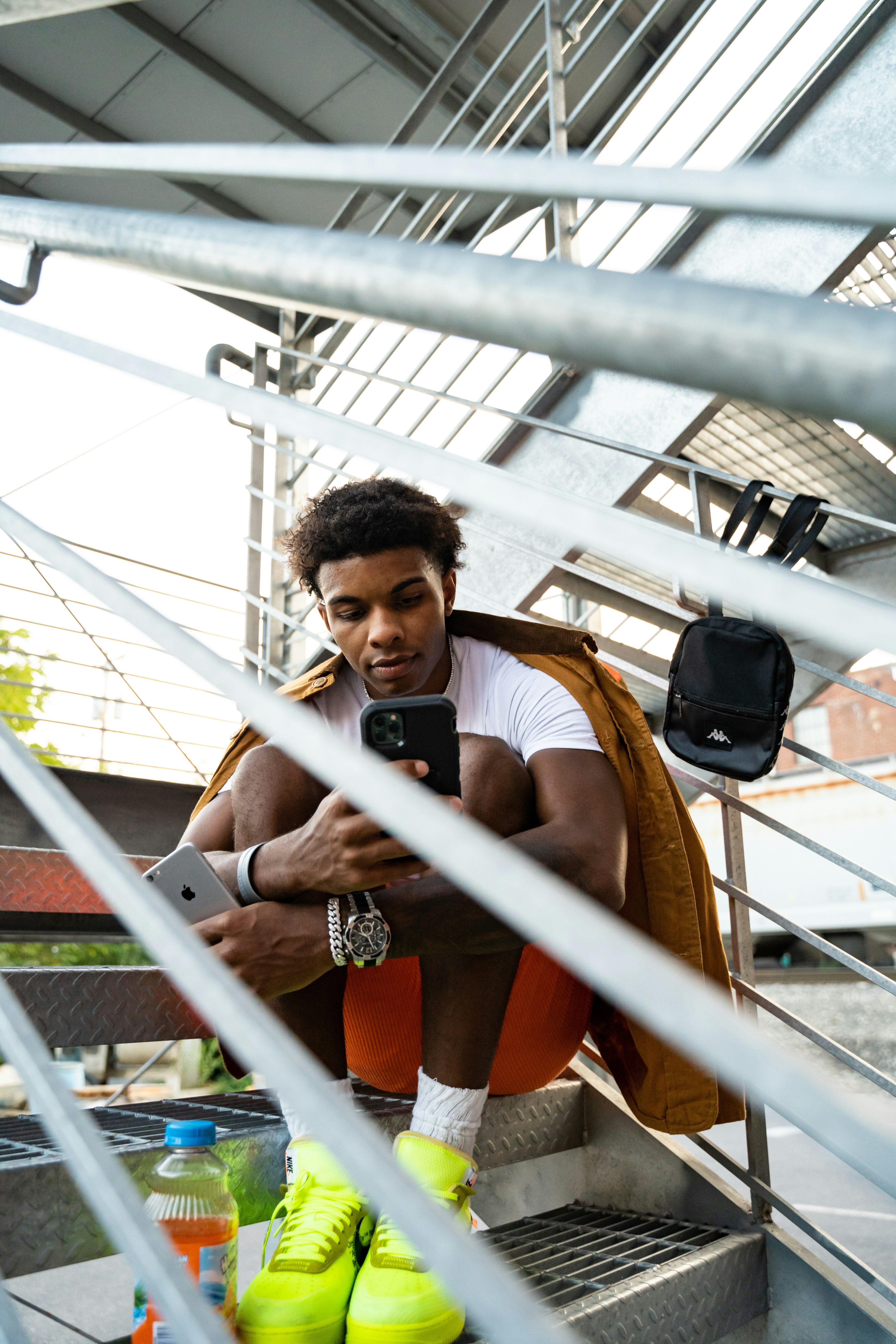 man in brown tank top holding black smartphone