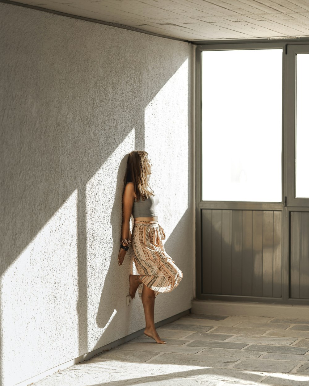 woman in brown dress standing beside gray wall