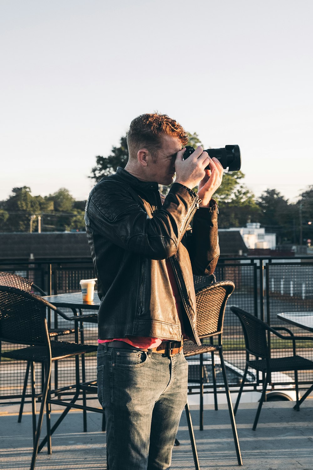 man in black jacket holding black dslr camera