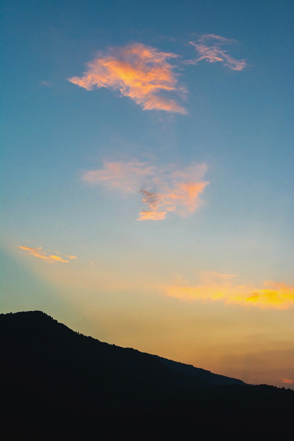 silhouette of mountain under cloudy sky during sunset