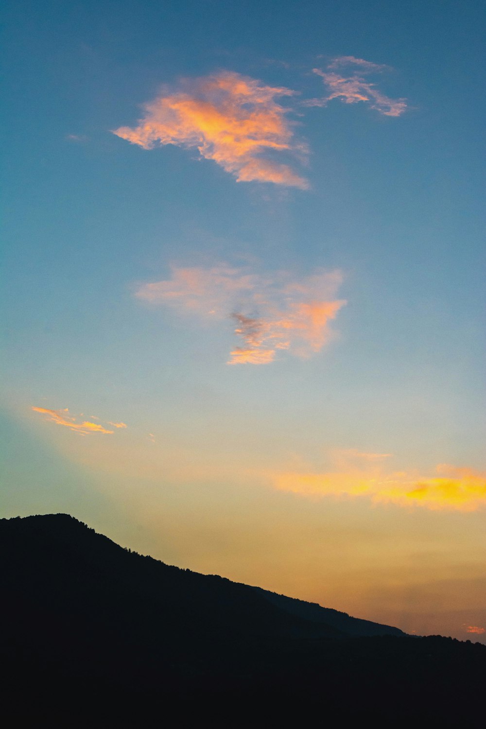 Silueta de la montaña bajo el cielo nublado durante la puesta del sol
