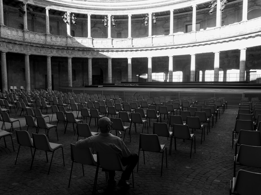 grayscale photo of people sitting on chairs