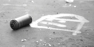 A close-up of a spray paint can next to a stencil of Banksy's iconic rat artwork.