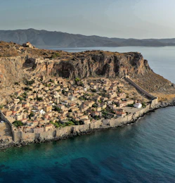 brown rocky mountain beside body of water during daytime