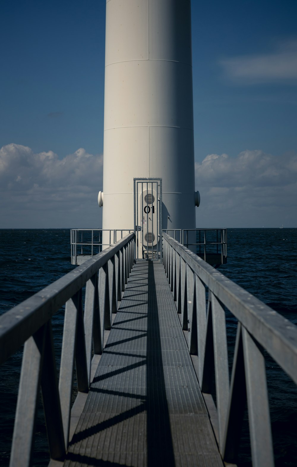 white and blue lighthouse near sea under blue sky during daytime