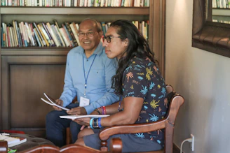 A mentor and mentee engaged in a thoughtful conversation in a sunlit study room filled with books.