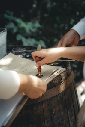 person holding gold and silver tube to stamp a document