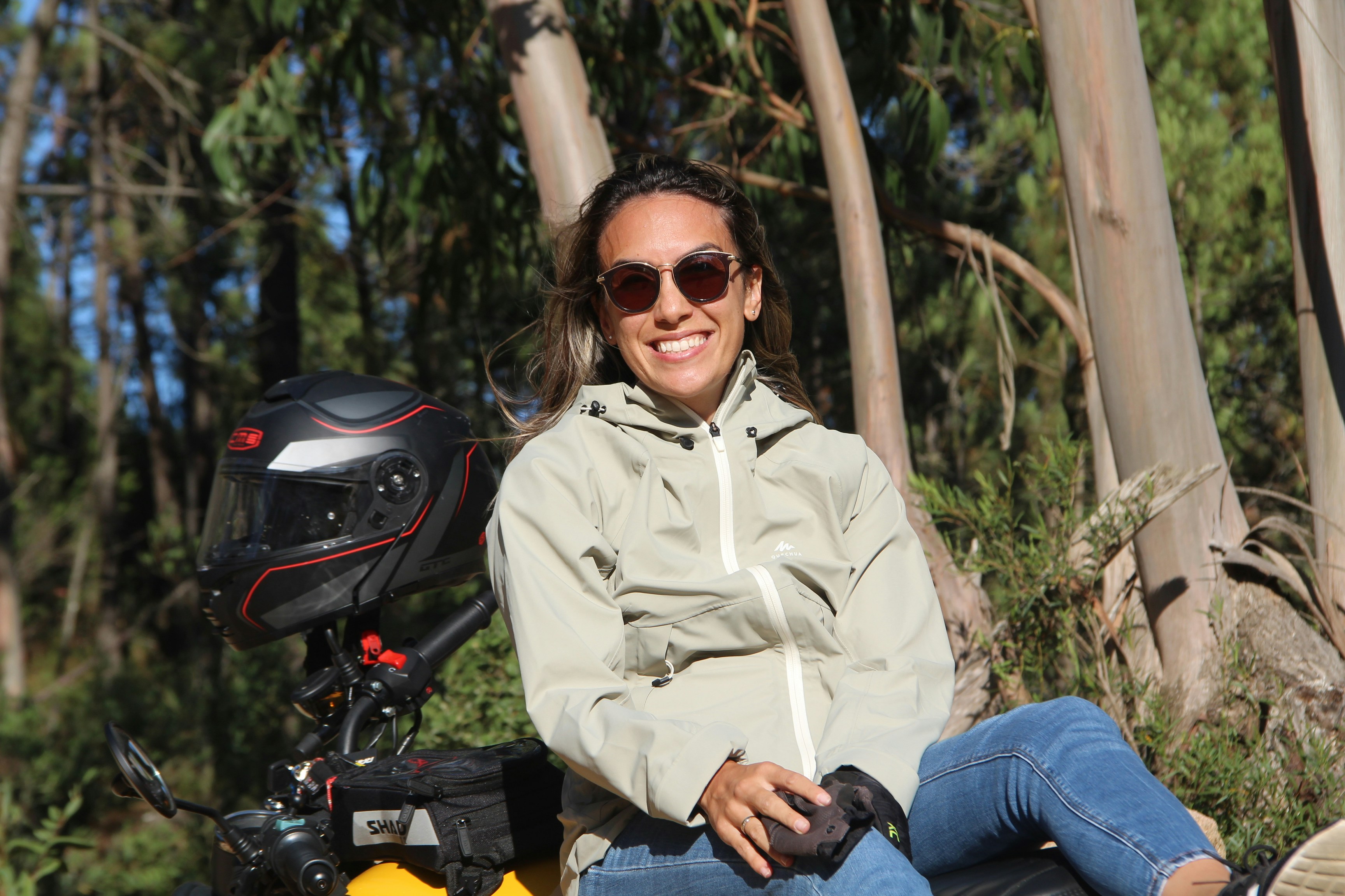 man in beige button up shirt and blue denim jeans sitting on motorcycle