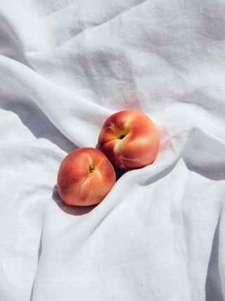 2 red apples on white textile