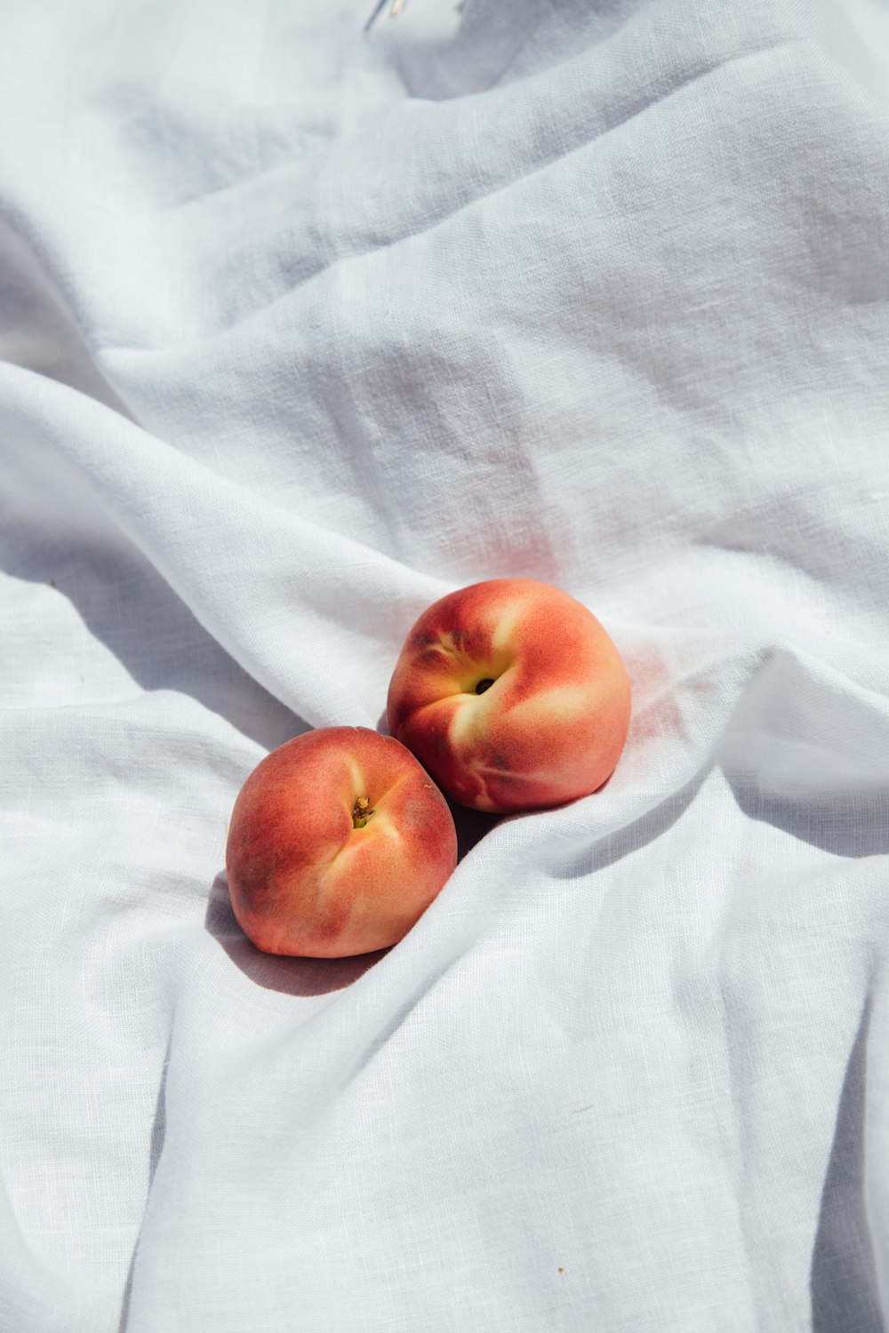 2 red apples on white textile