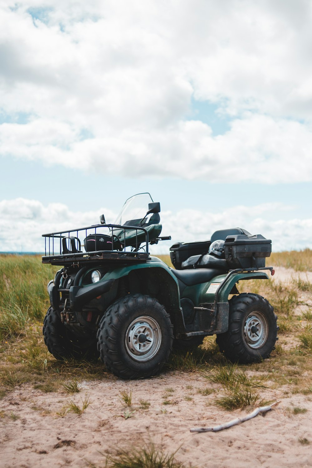 green and black atv on green grass field under white clouds during daytime