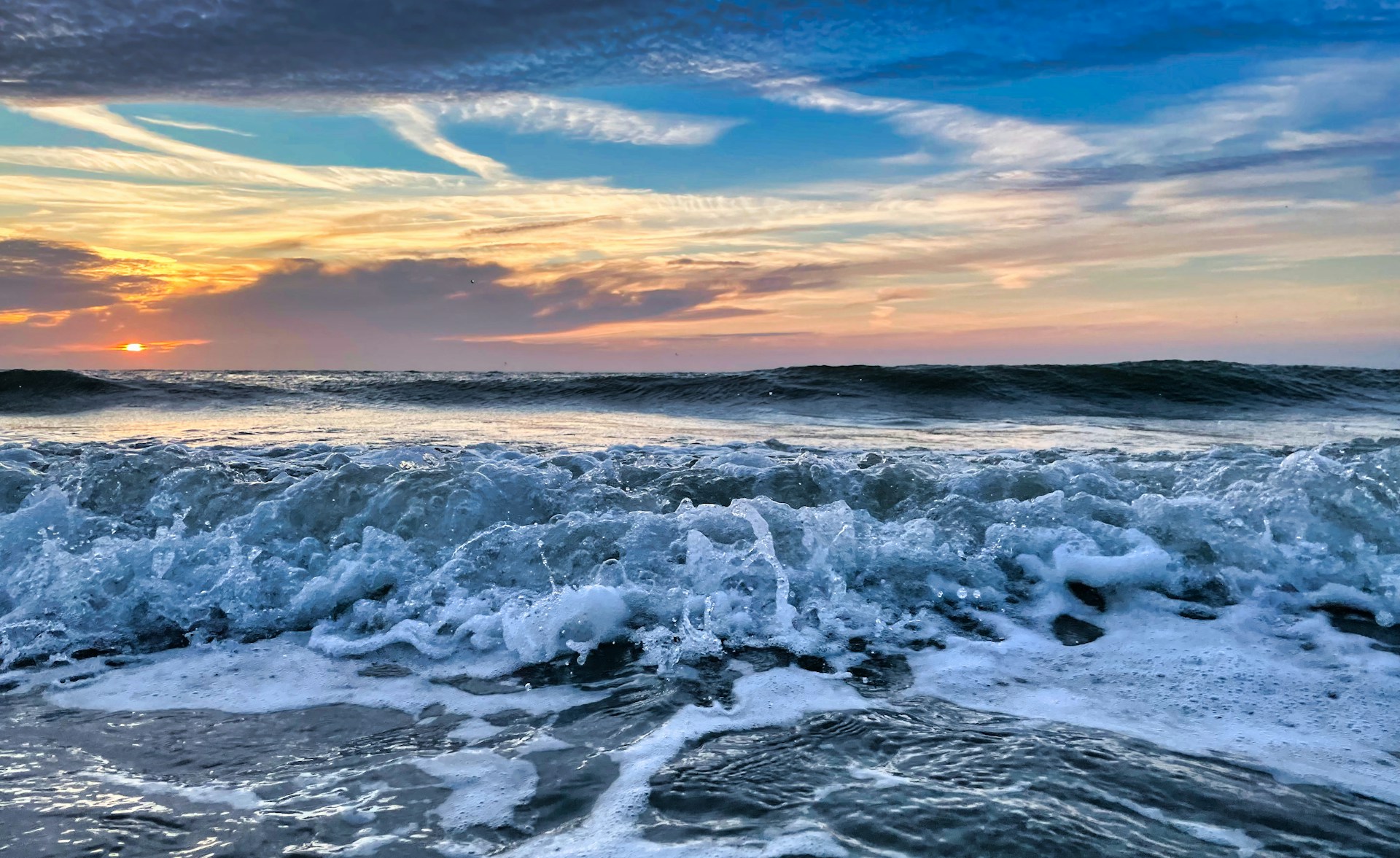 ocean waves crashing on shore during sunset