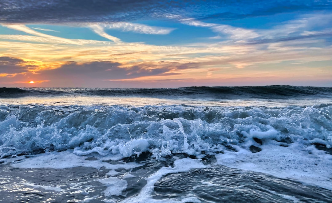 ocean waves crashing on shore during sunset