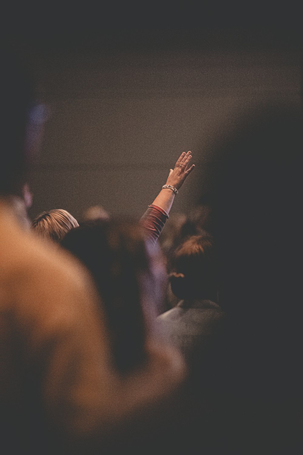 people raising their hands in front of crowd