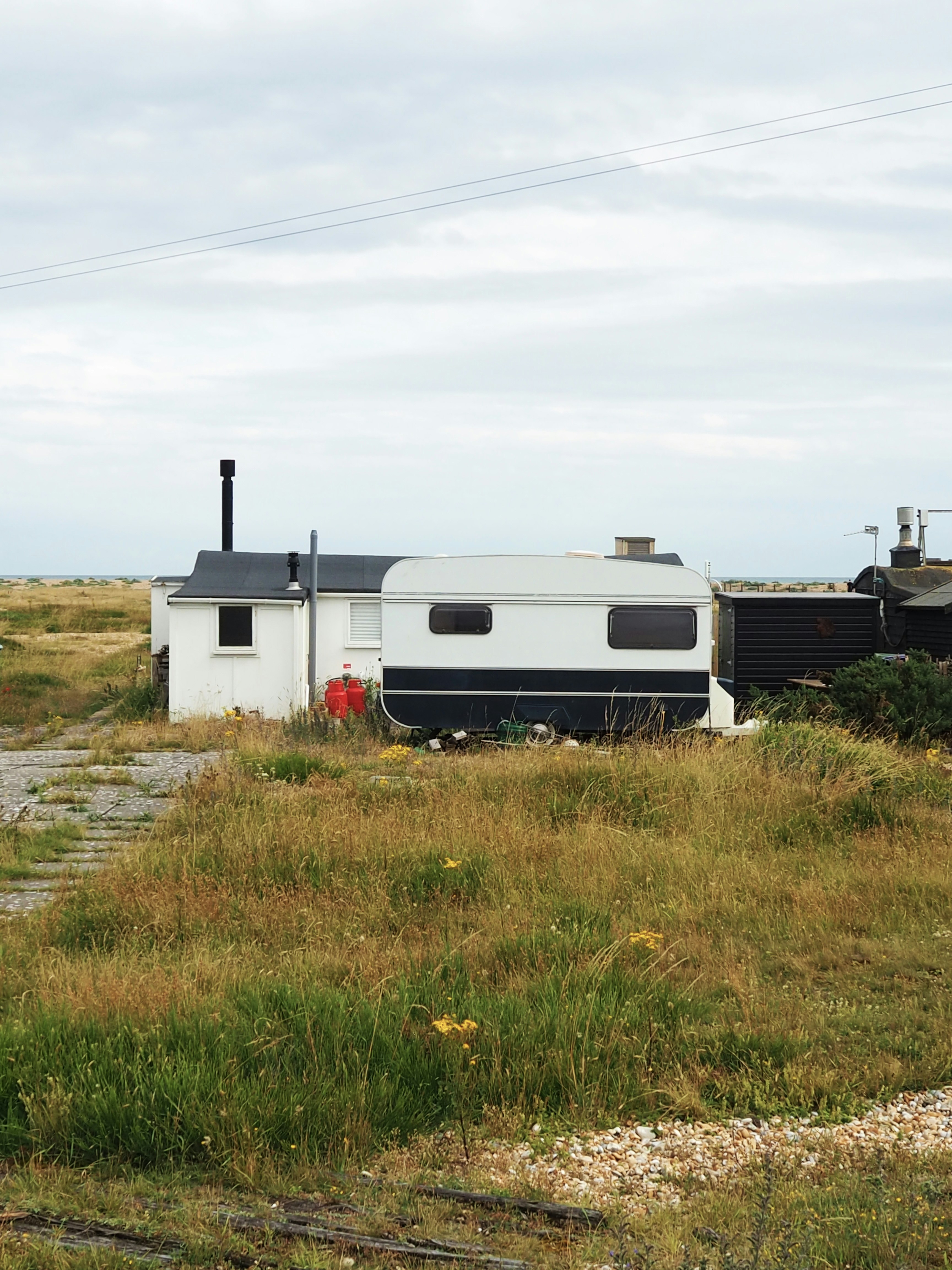 white and black rv trailer on green grass field under white cloudy sky during daytime