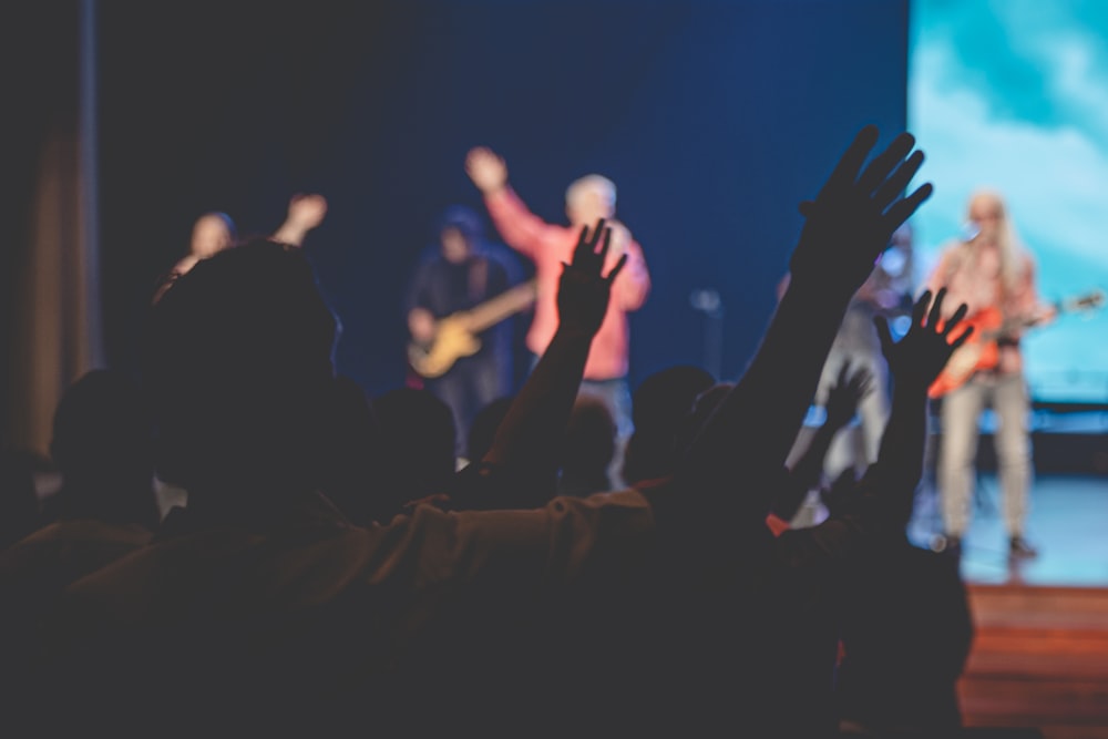 people raising their hands in front of crowd