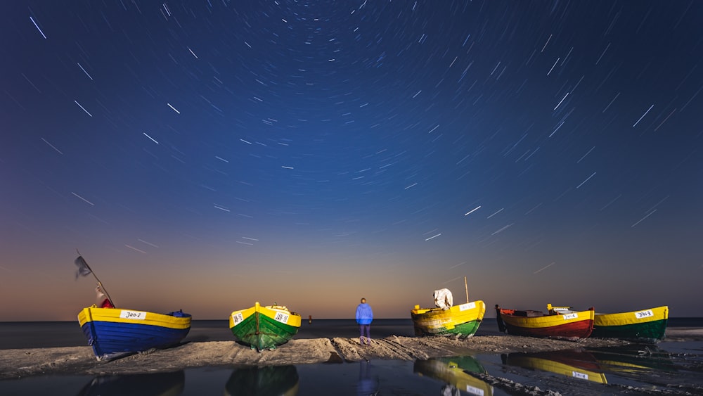 Gelbe und grüne Plastikboote auf braunem Sand während der Nacht