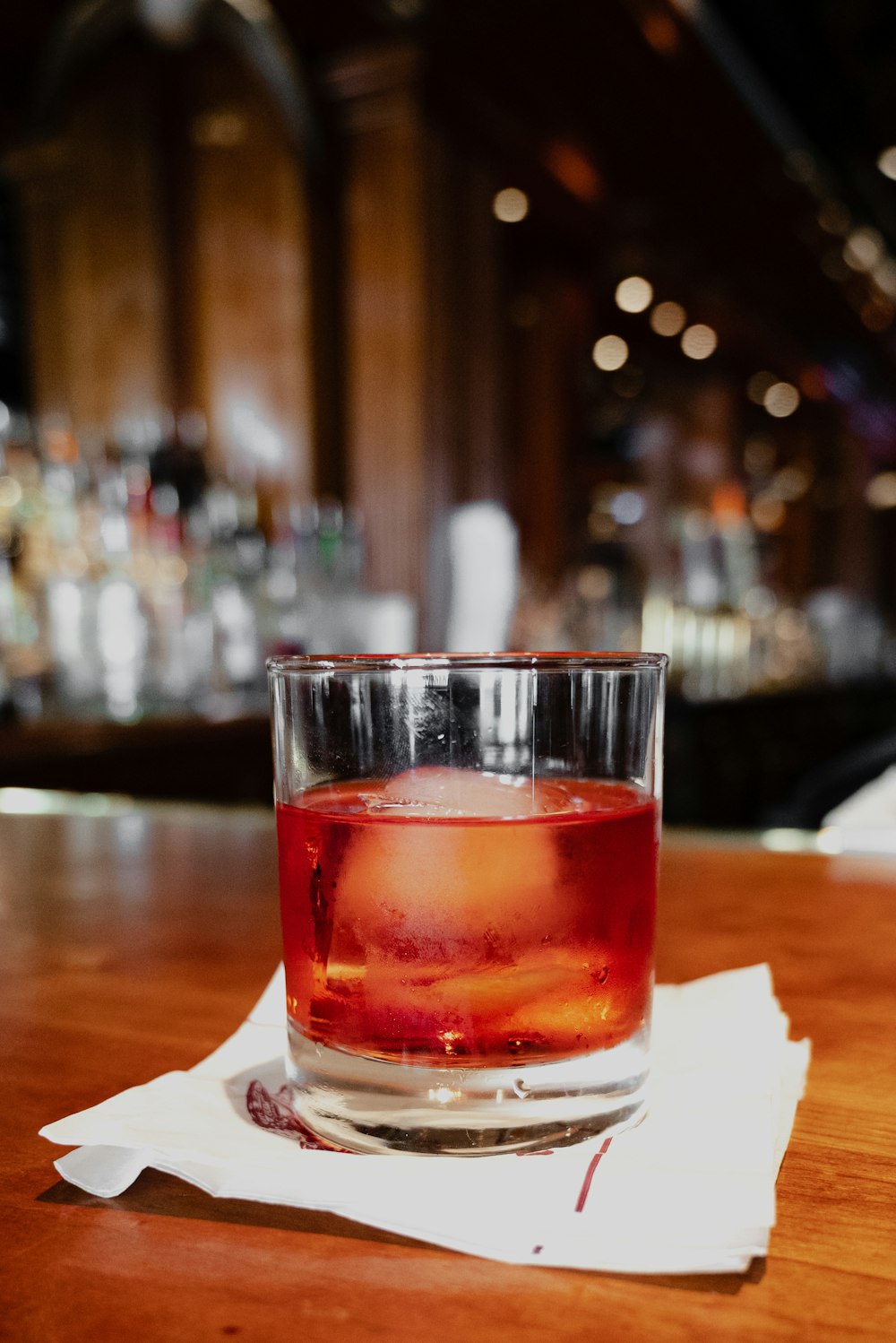 verre à boire transparent avec un liquide rouge sur une table blanche