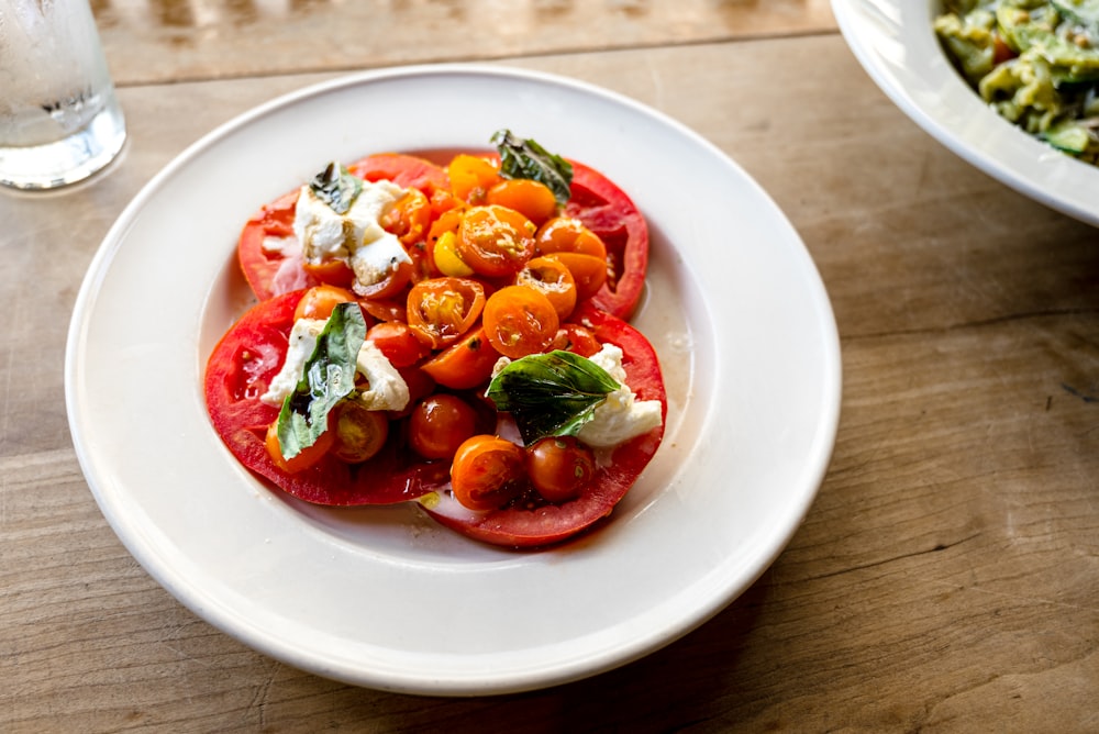 rodajas de tomate y verdura de hoja verde en plato de cerámica blanca