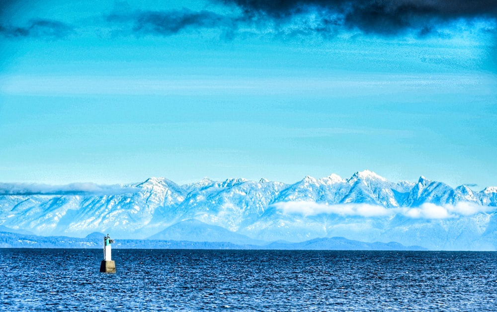 white and black lighthouse near snow covered mountain during daytime