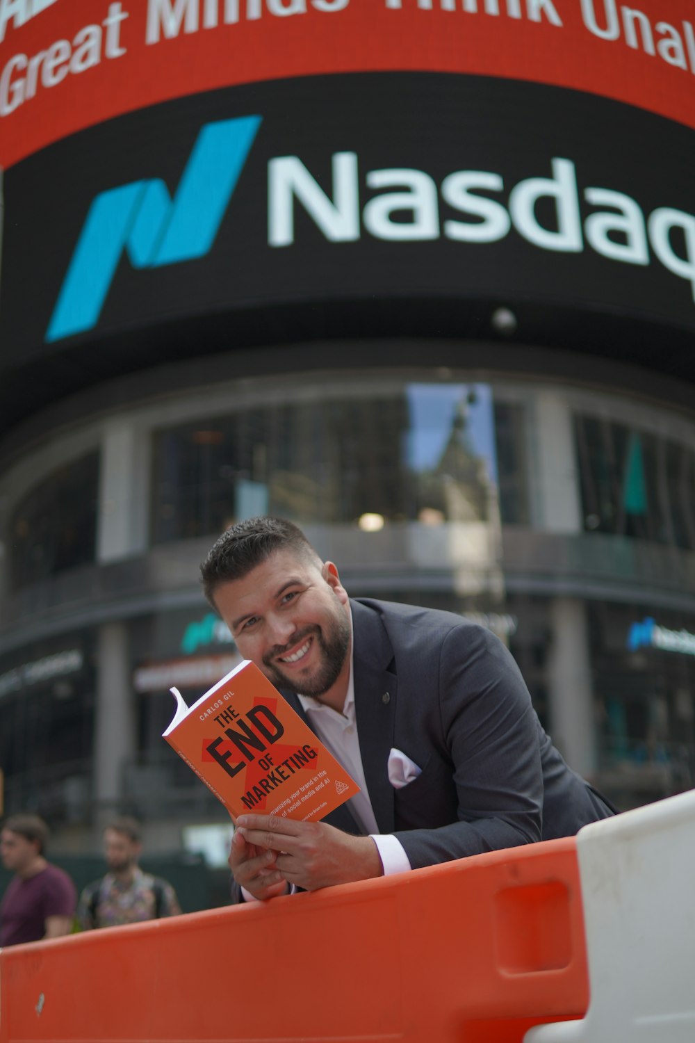 man in black suit jacket holding orange book