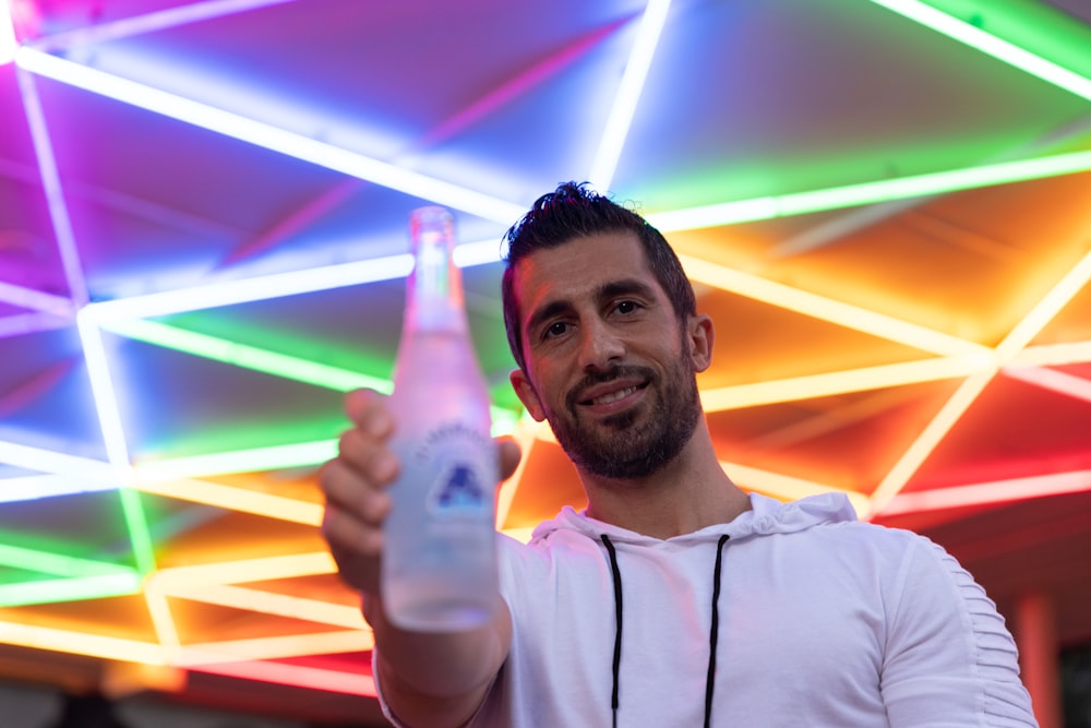 흰색과 파란색 플라스틱 병을 들고 있는 흰색 크루넥 셔츠를 입은 남자