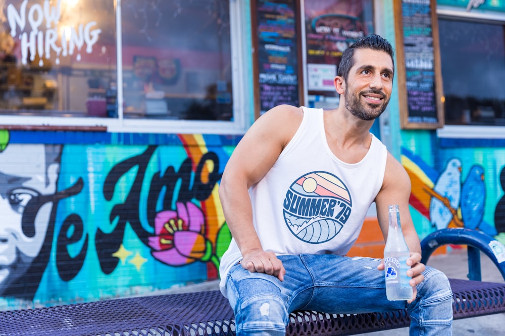 man in white tank top and blue denim jeans sitting on blue chair