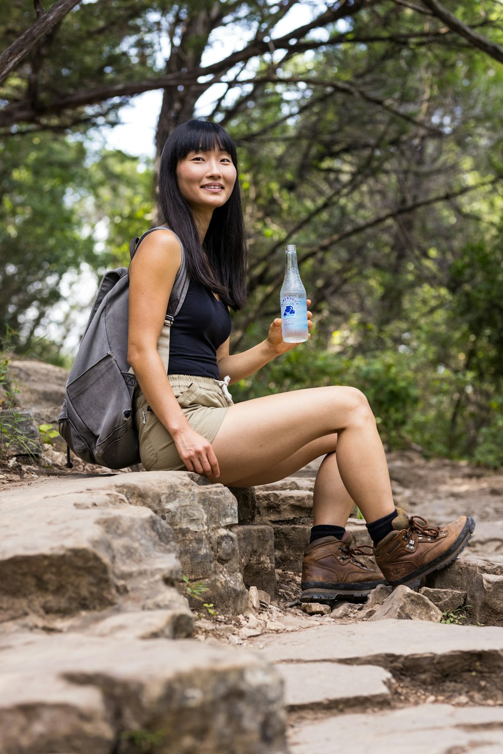 woman in black tank top and brown shorts sitting on rock