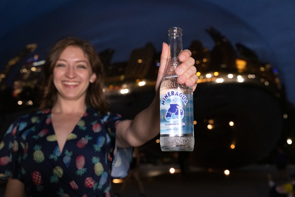 woman in blue and red floral shirt holding clear glass bottle