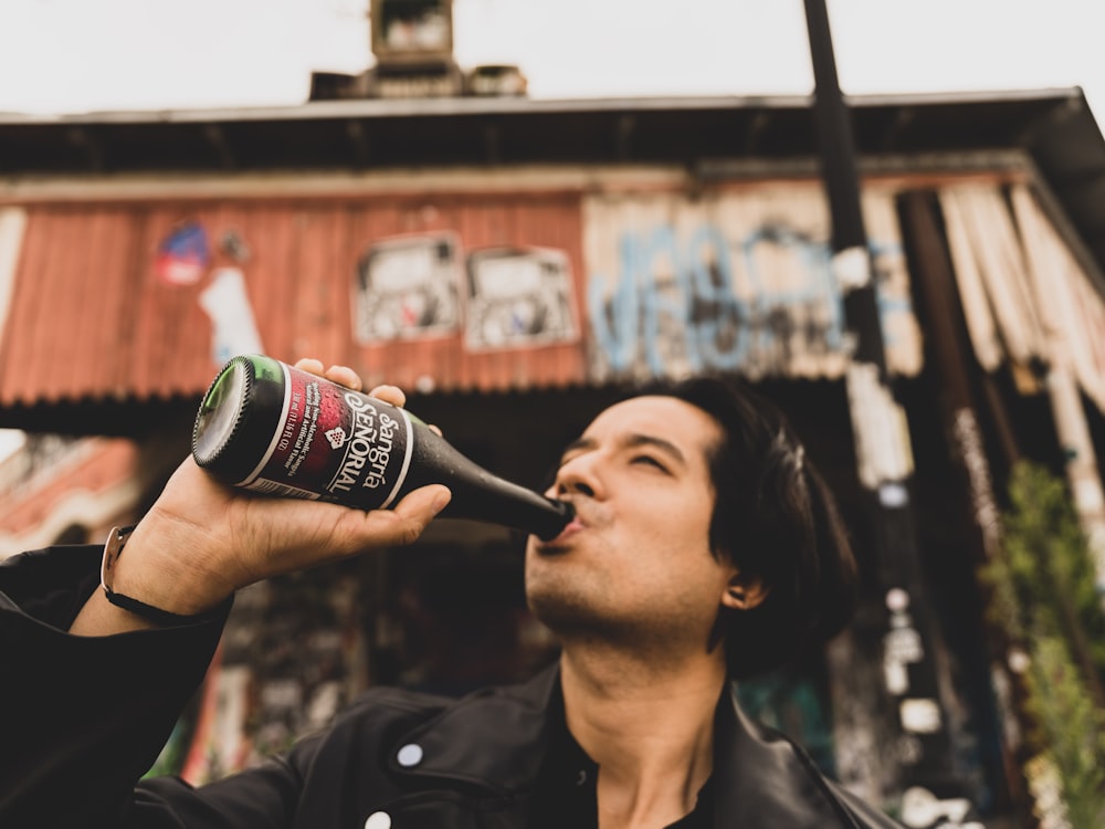 woman in black jacket drinking coca cola bottle