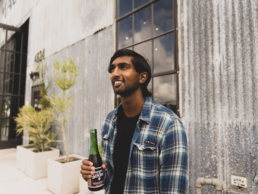 man in blue and white plaid button up shirt holding bottle