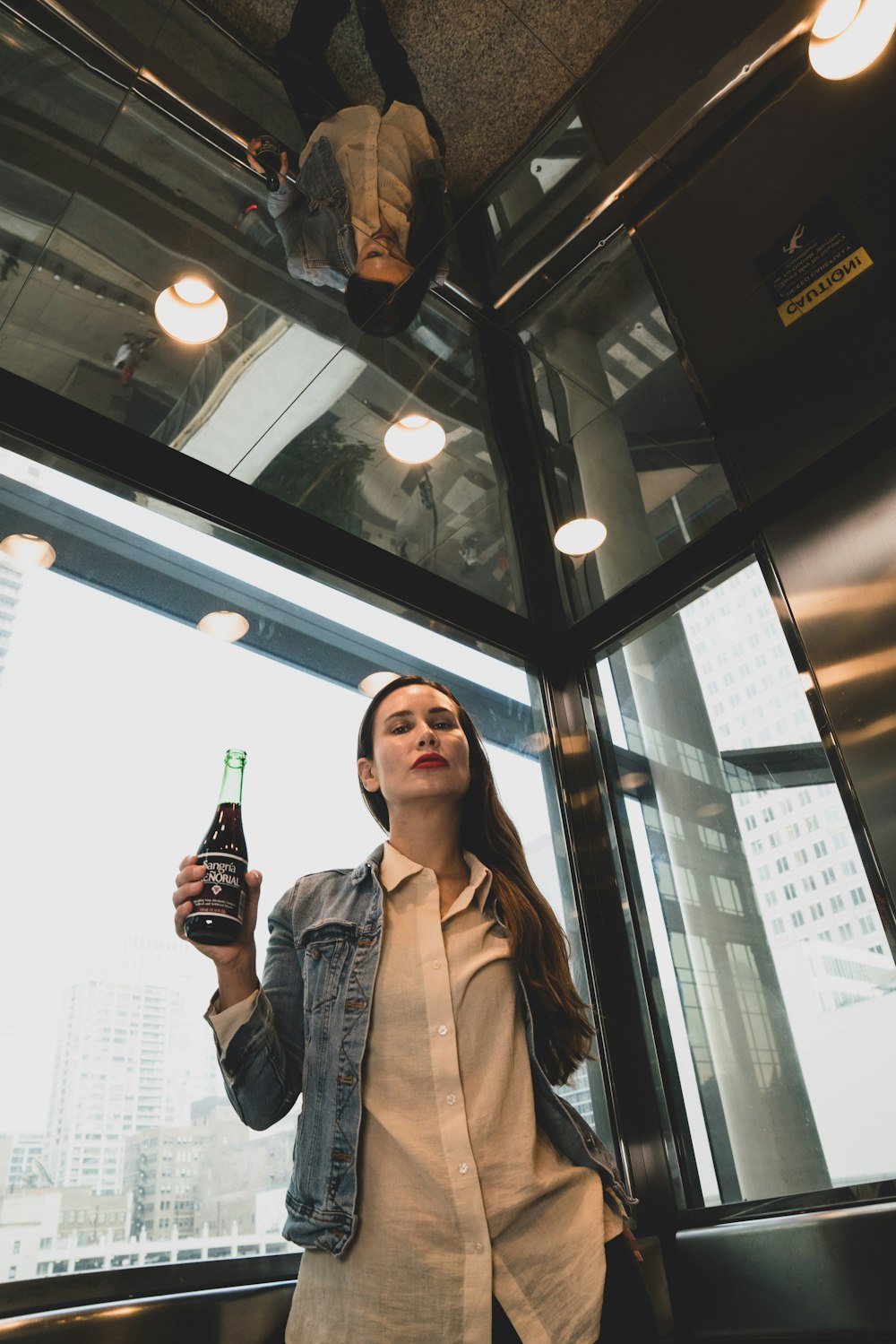 woman in blue denim jacket holding bottle