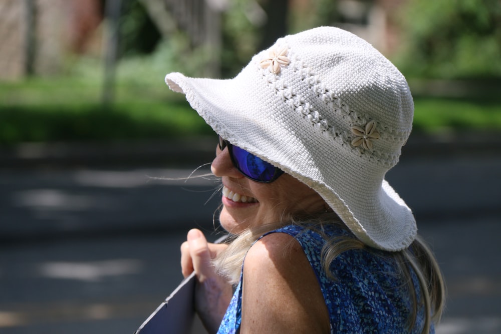woman in blue tank top wearing white sun hat and sunglasses