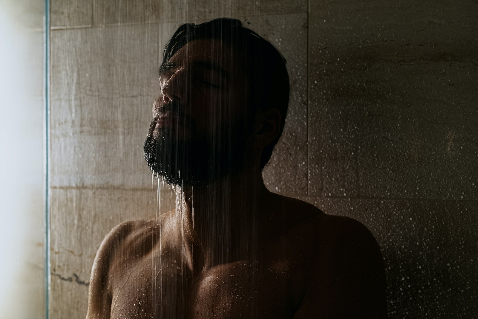 Man rinsing his hair under a warm shower