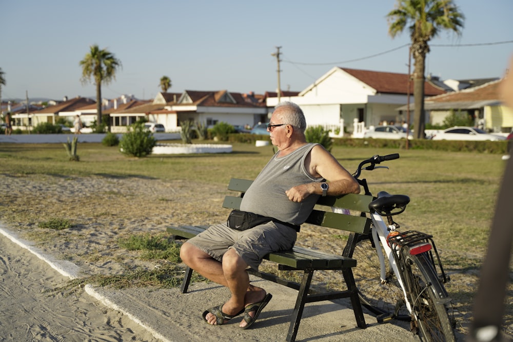 man in gray t-shirt sitting on black wooden bench during daytime