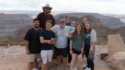 A group of diverse young people smiling together at an ancient holy site under a clear sky.