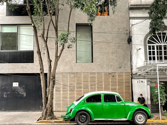 A vibrant green Mini Aceman parked in front of a modern urban building.