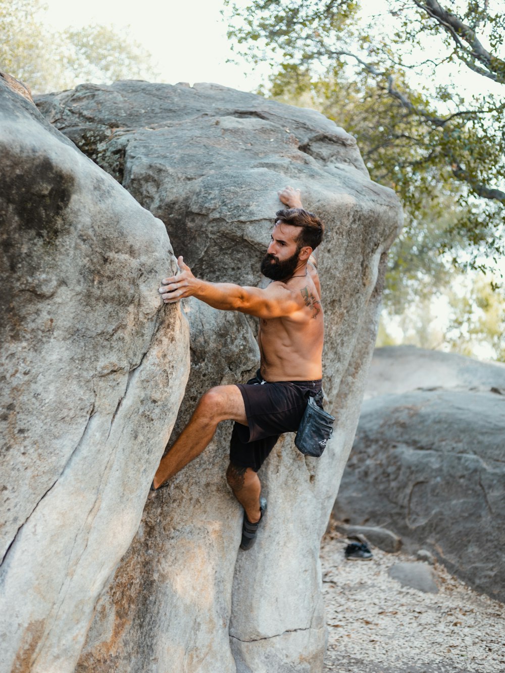 topless man in black shorts climbing on brown rock during daytime