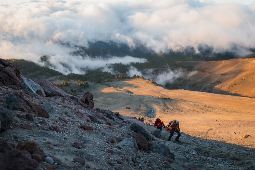 people sitting on rock formation under white clouds during daytime