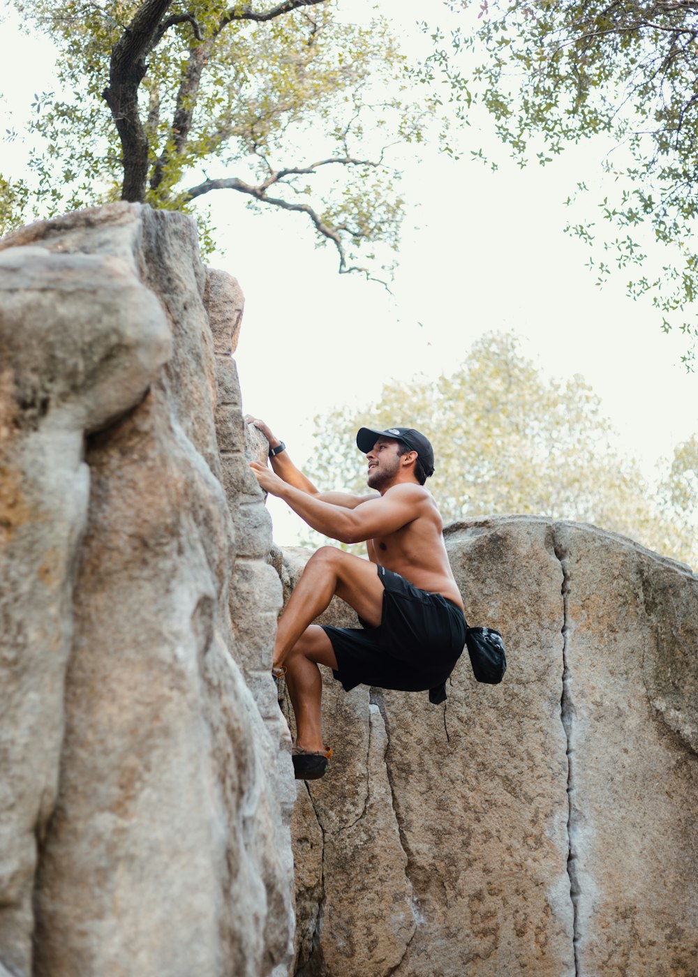 hombre en pantalones cortos negros escalando en una formación rocosa marrón durante el día