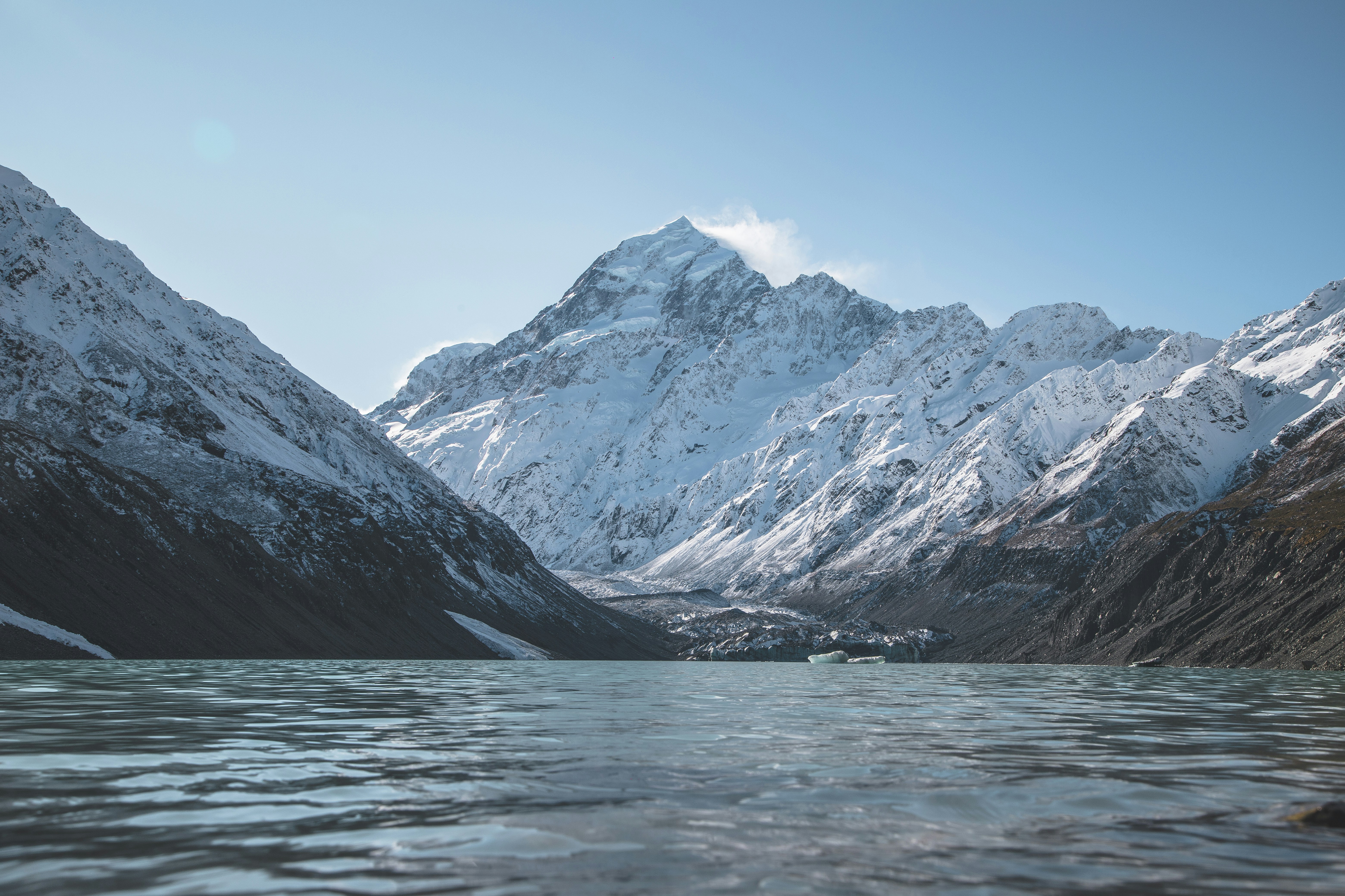 snow covered mountains near body of water during daytime