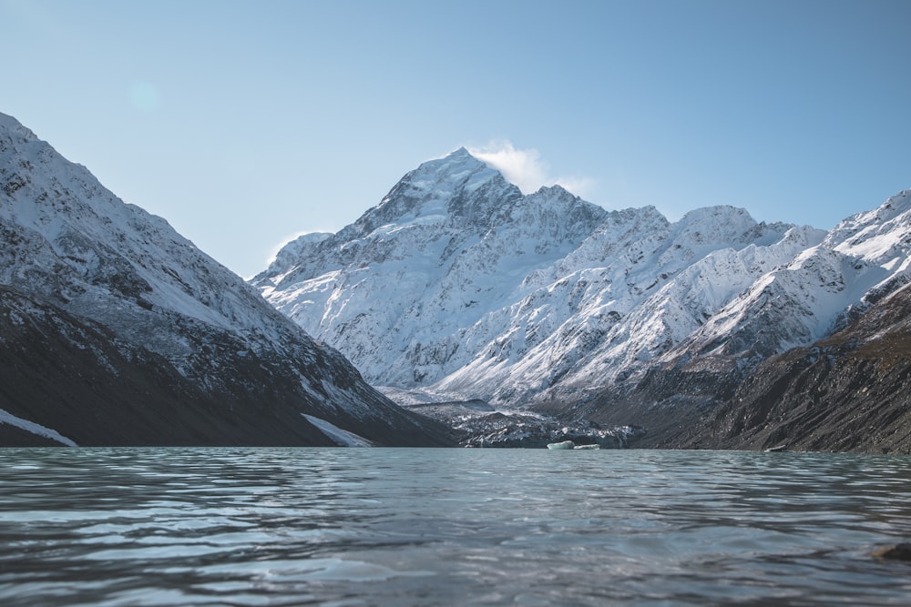 montagnes enneigées près d’un plan d’eau pendant la journée