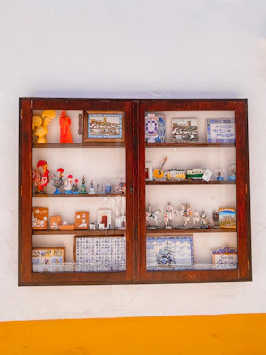 A quirky collection of travel souvenirs arranged on a shelf against a textured wall.